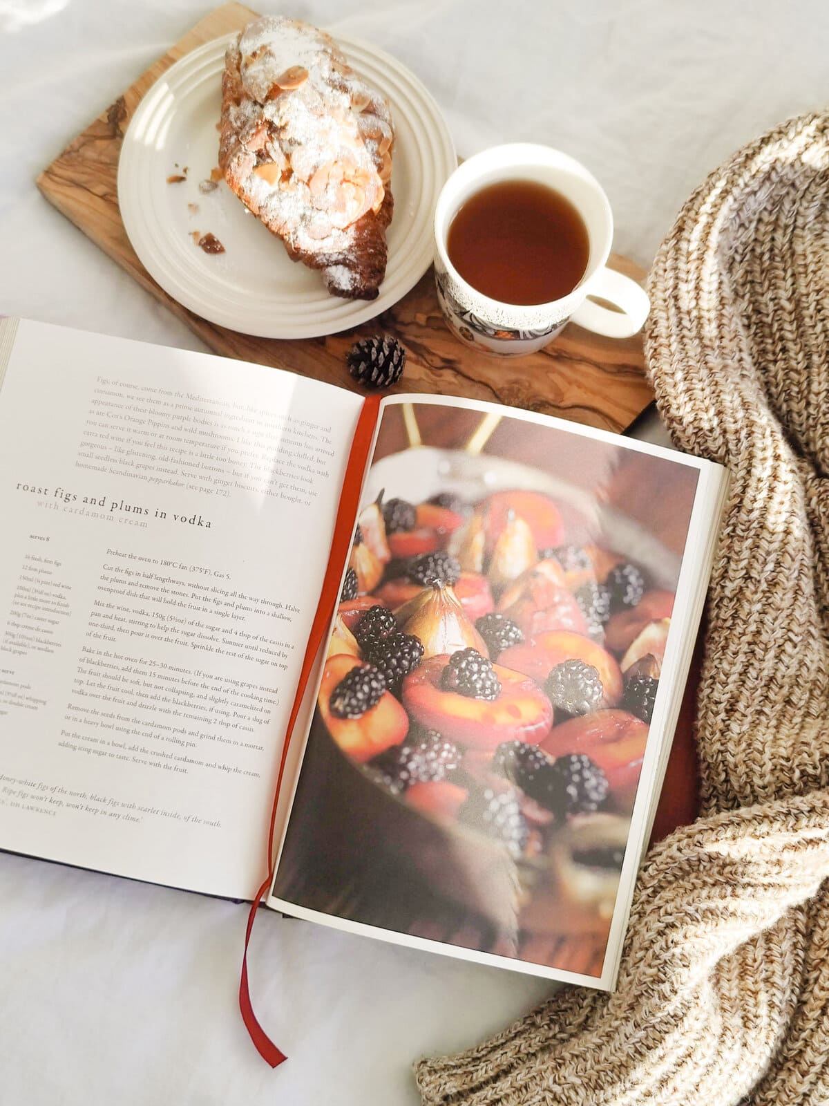 Roast figs and plums in vodka recipe page in Roast Figs, Sugar Snow by Diana Henry in cozy setting with tea and pastry