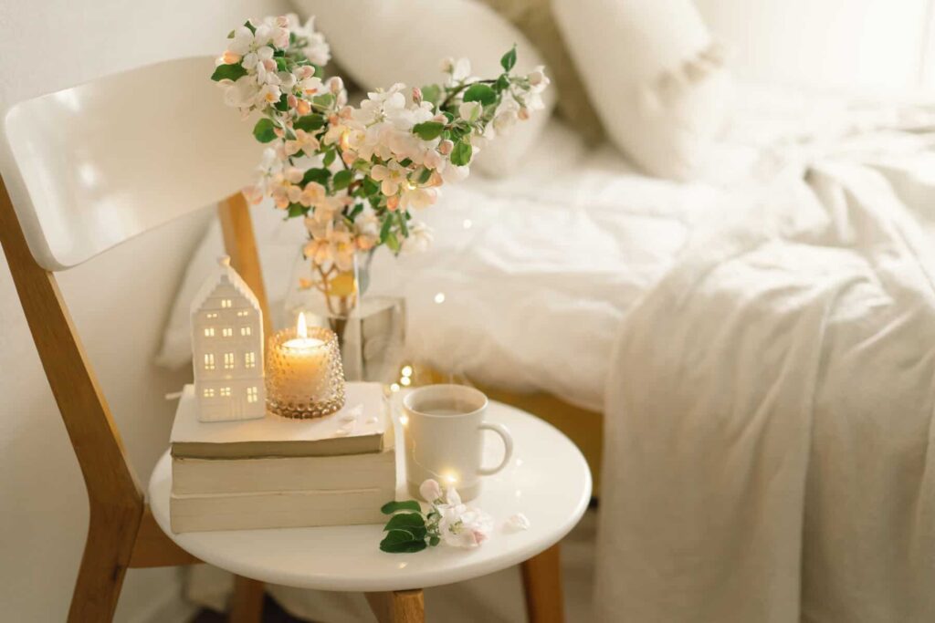 Book, hot cup tea, candle and vase with apple spring flowers.