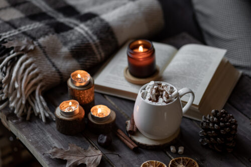 Cozy home with hot chocolate and candles next to books